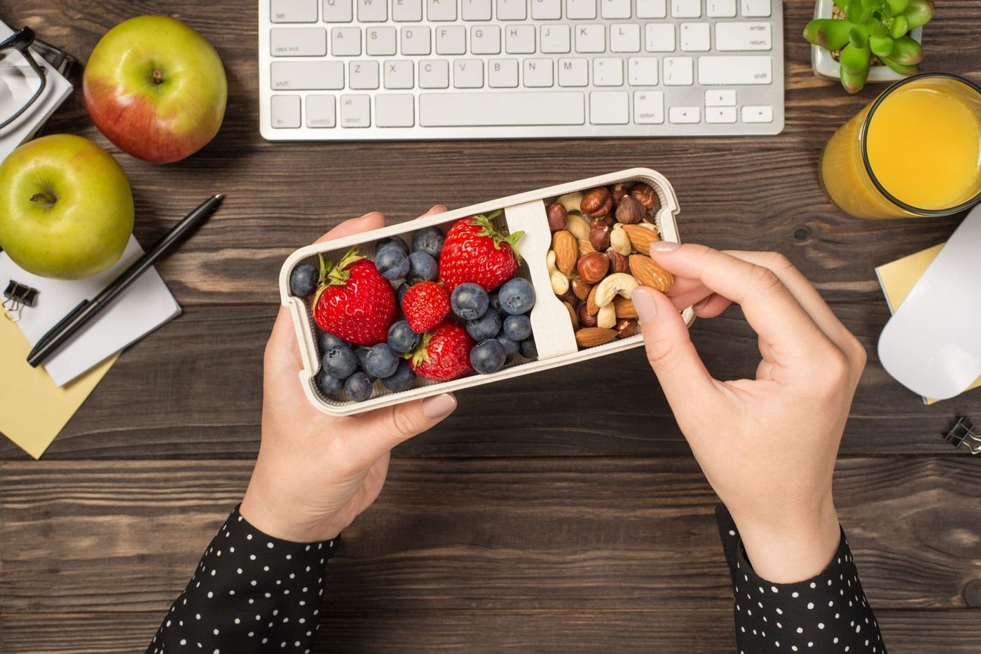 Händer som håller en snackbox med frukt och nötter